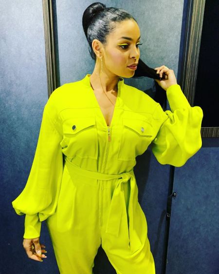 Jordin Sparks in a green-yellow dress poses for a picture.